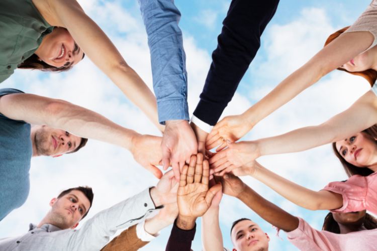 Team of people putting their hands into the middle of a circle