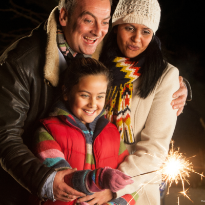 Male and female with child in front holding a sparkler